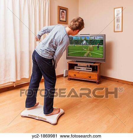 Stock Image - A 9 year old boy playing on a Nintendo Wii Fit board. Fotosearch