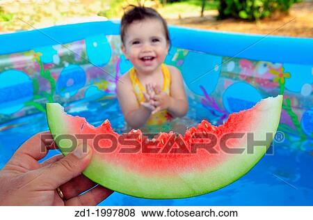 A baby girl eats a cold watermelon in a baby pool in a very hot day. View Large Photo Image Stock Photo - A baby girl eats a cold watermelon in a baby pool in a very hot day.. Fotosearch