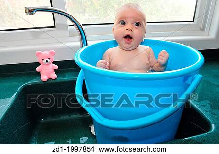 A baby in a blue bucket cools off in the summer heat. View Large Photo Image Picture - A baby in a blue bucket cools off in the summer heat.. Fotosearch