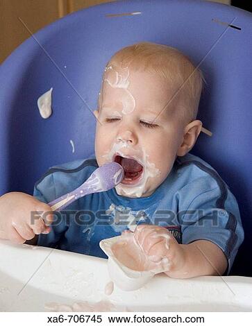 A baby makes a big mess as he sits in his high chair feeding himself strawberry yoghurt. View Large Photo Image Stock Photography - A baby makes a big mess as he sits in his high chair feeding himself strawberry yoghurt.. Fotosearch