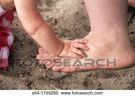 A baby puts her hand on her mothers foot at the beach. View Large Photo Image Stock Image - A baby puts her hand on her mothers foot at the beach.. Fotosearch