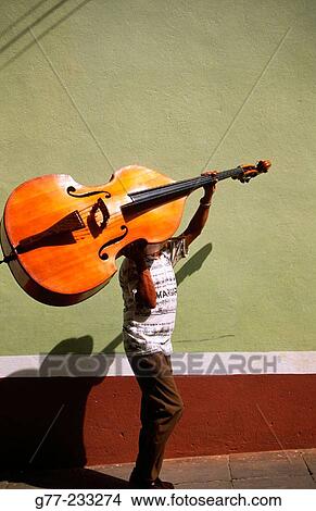 Picture - A bass player carrying his double bass. Trinidad de Cuba. Cuba. Fotosearch