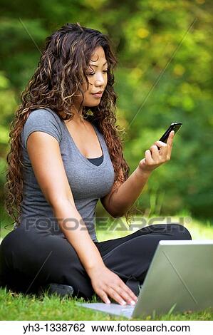 A beautiful African American woman using laptop while holding a smartphone View Large Photo Image Stock Image - A beautiful African American woman using laptop while holding a smartphone. Fotosearch