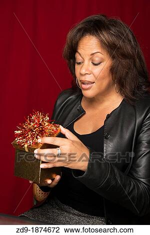 A beautiful middle-aged black woman peeks into a gift box View Large Photo Image Stock Image - A beautiful middle-aged black woman peeks into a gift box. Fotosearch