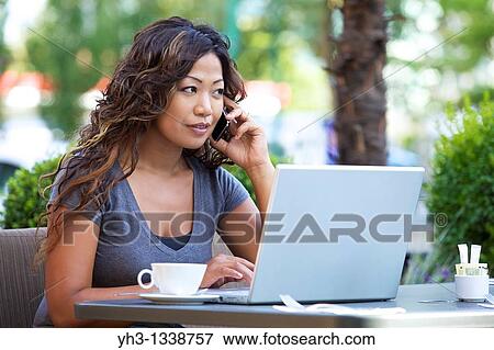 A beautiful woman using laptop while holding a smartphone View Large Photo Image Stock Photo - A beautiful woman using laptop while holding a smartphone. Fotosearch