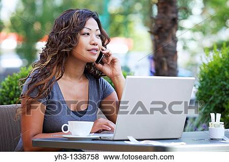 A beautiful woman using laptop while holding a smartphone View Large Photo Image Stock Photo - A beautiful woman using laptop while holding a smartphone. Fotosearch
