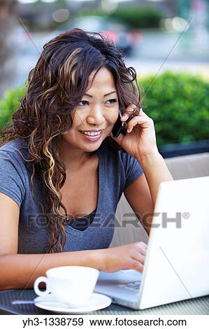 A beautiful woman using laptop while holding a smartphone View Large Photo Image Stock Photo - A beautiful woman using laptop while holding a smartphone. Fotosearch