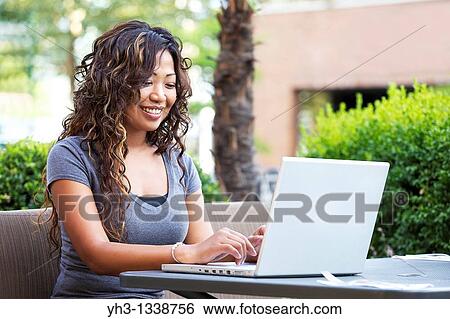 A beautiful woman using laptop while holding a smartphone View Large Photo Image Stock Photograph - A beautiful woman using laptop while holding a smartphone. Fotosearch