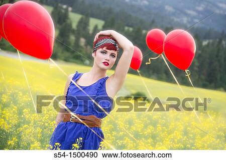 Stock Image - A beautiful young caucasian female in a canola field with balloons near Spokane, Washington, USA.. Fotosearch