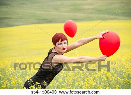 Stock Image - A beautiful young caucasian female in a canola field with balloons near Spokane, Washington, USA.. Fotosearch