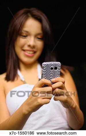 A beautiful young lady enjoying her smartphone View Large Photo Image Stock Photograph - A beautiful young lady enjoying her smartphone. Fotosearch