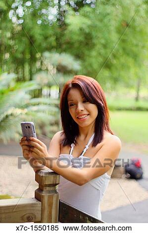 Stock Photography - A beautiful young lady enjoying her smartphone. Fotosearch