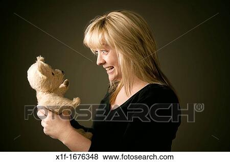a blonde haired teenage girl woman pulling a face and playing with her old battered teddy bear View Large Photo Image Stock Photo - a blonde haired teenage girl woman pulling a face and playing with her old battered teddy bear. Fotosearch