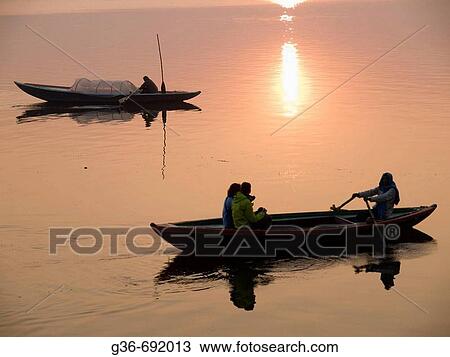 Stock Image - A boat man rows his boat to show visitors life along the holy river Ganges, an important pilgrimge site for Hindu? s, in Varanasi, Uttar Pradesh, India. Fotosearch
