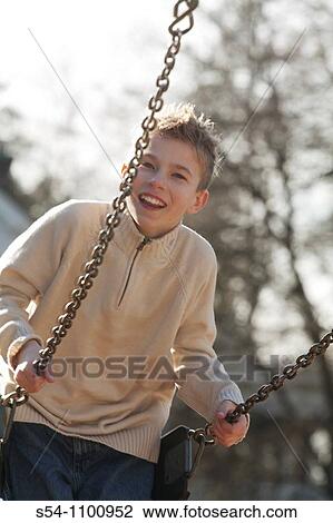 Stock Image - A boy, 10-15 years old, on a swing. Fotosearch