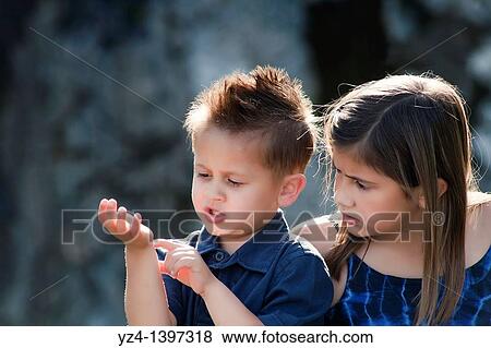 A boy and girl looking at the boys arm. View Large Photo Image Stock Photo - A boy and girl looking at the boys arm.. Fotosearch