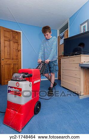 Picture - A boy cleaning his bedroom carpet with a hired RugDoctor carpet cleaning machine. Fotosearch