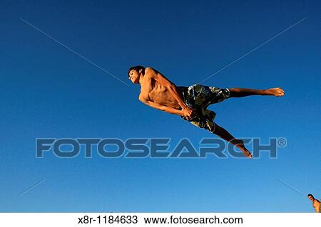 Stock Image - A boy jumps into the sea at? Bikini? beach during a summer day in the northern Spanish town of Santander. Fotosearch