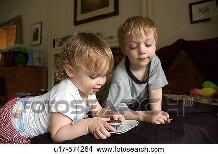 A boy looks at the toy cookies a young girl is playing with in their home. View Large Photo Image Picture - A boy looks at the toy cookies a young girl is playing with in their home.. Fotosearch