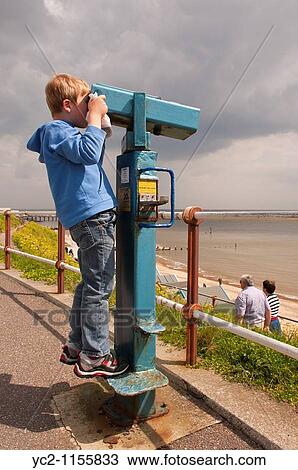 A boy looks through the pay and view telescope at the beach in Southwold, Suffolk, England, Great Britain, Uk View Large Photo Image Stock Image - A boy looks through the pay and view telescope at the beach in Southwold, Suffolk, England, Great Britain, Uk. Fotosearch