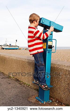 A boy of seven looks through a seaside telescope at Aldeburgh, Suffolk, England, Britain, Uk View Large Photo Image Stock Image - A boy of seven looks through a seaside telescope at Aldeburgh, Suffolk, England, Britain, Uk. Fotosearch