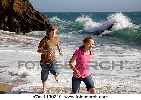 A boy playfully chases a young girl on a beach in Santa Cruz, California View Large Photo Image Stock Photo - A boy playfully chases a young girl on a beach in Santa Cruz, California. Fotosearch