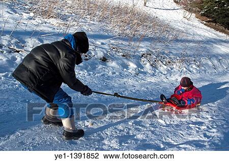 A boy pulling a little girl along on a sled on a snowy path View Large Photo Image Stock Image - A boy pulling a little girl along on a sled on a snowy path. Fotosearch