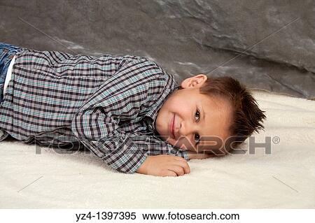 Stock Photography - A boy smiling and laying down indoors. Fotosearch
