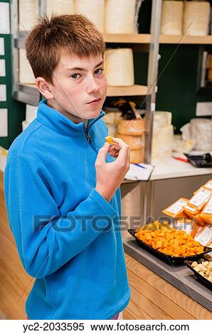 Stock Photography - A boy tasting cheese in The cheese shop in the Wensleydale Creamery visitor centre in Hawes in Wensleydale, North Yorkshire, England, Britain, Uk.. Fotosearch