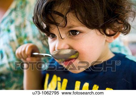 A boy trying to eat with a big spoon. View Large Photo Image Stock Photography - A boy trying to eat with a big spoon.. Fotosearch
