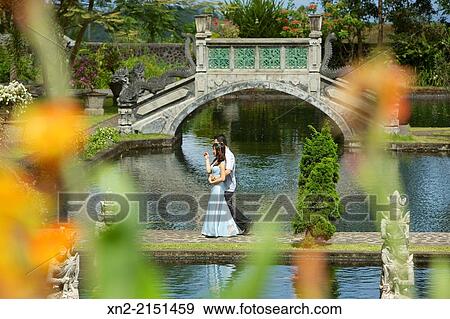 A bride and groom walk between ponds at Tirtagangga Water Palace, Karangasem, Bali, Indonesia View Large Photo Image Stock Photo - A bride and groom walk between ponds at Tirtagangga Water Palace, Karangasem, Bali, Indonesia. Fotosearch
