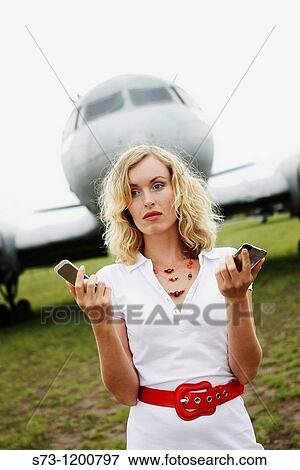 A business woman with two mobiles phones next to a plane View Large Photo Image Stock Photo - A business woman with two mobiles phones next to a plane. Fotosearch