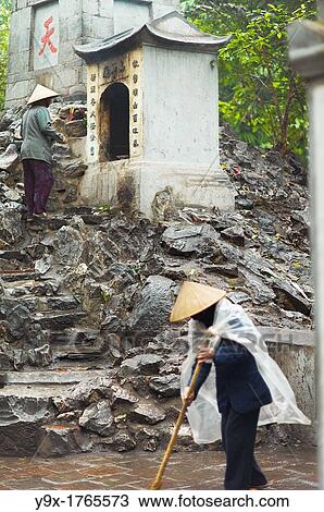 A caretaker wearing a traditional Non La hat sweeping a shrine at the Hoan Kiem Lake in Vietnam View Large Photo Image Stock Image - A caretaker wearing a traditional Non La hat sweeping a shrine at the Hoan Kiem Lake in Vietnam. Fotosearch