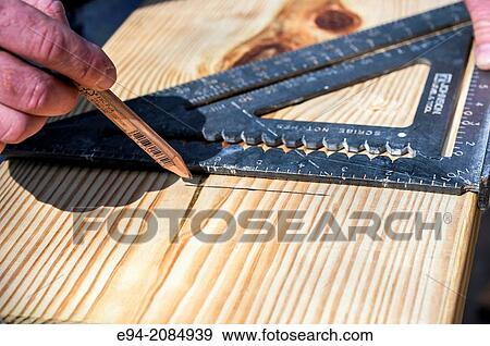 A carpenter marks a piece of lumber with a straight edge before cutting. View Large Photo Image Stock Photo - A carpenter marks a piece of lumber with a straight edge before cutting.. Fotosearch