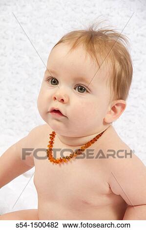 Stock Image - A caucasian baby boy indoors, 8 months old, wearing a baltic amber necklace for teething pain.. Fotosearch