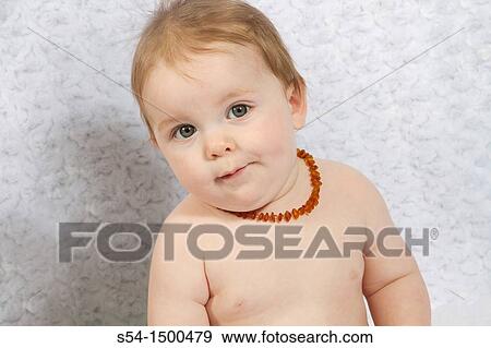 Stock Photo - A caucasian baby boy indoors, 8 months old, wearing a baltic amber necklace for teething pain.. Fotosearch