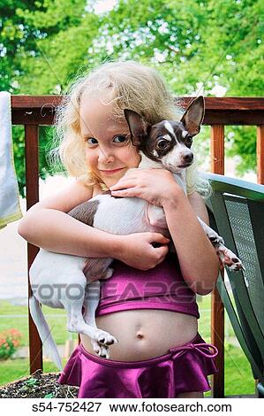 Stock Photo - A Caucasian girl, 5-10, holds a Chihuahua. Fotosearch