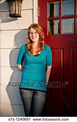 A Caucasian teenage girl standing against a red door View Large Photo Image Stock Image - A Caucasian teenage girl standing against a red door. Fotosearch
