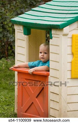 Stock Photo - A caucasian toddler in a playhouse outdoors. Fotosearch