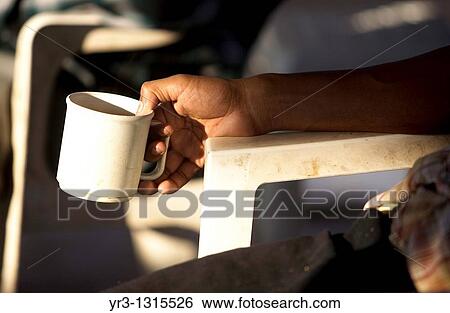 Stock Photograph - A Central American migrant traveling across Mexico to work in the United States drinks a cup of coffee at the Catholic priest Alejandro Solalinde's shelter Hermanos del Camino Brothers of the road. Fotosearch