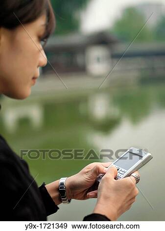 A Chinese businesswoman taps away on her PDA smart phone. View Large Photo Image Stock Photo - A Chinese businesswoman taps away on her PDA smart phone.. Fotosearch