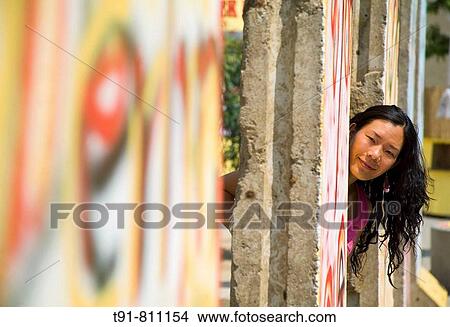 a Chinese tourist is posing at the open Berlin wall in Germany View Large Photo Image Picture - a Chinese tourist is posing at the open Berlin wall in Germany. Fotosearch