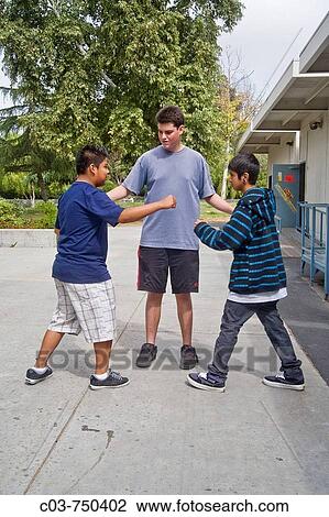 A classmate intervenes in a dispute between two young teenage boys on a Southern California middle school campus View Large Photo Image Stock Image - A classmate intervenes in a dispute between two young teenage boys on a Southern California middle school campus. Fotosearch