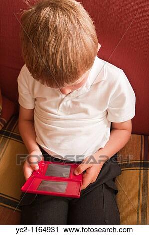 A close up picture of a six year old boy playing on a nintendo DS handheld computer game console in the Uk View Large Photo Image Stock Image - A close up picture of a six year old boy playing on a nintendo DS handheld computer game console in the Uk. Fotosearch
