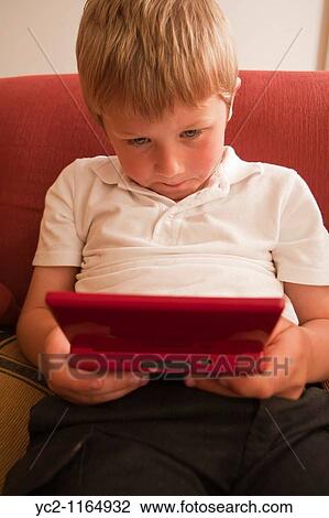 Stock Image - A close up picture of a six year old boy playing on a nintendo DS handheld computer game console in the Uk. Fotosearch