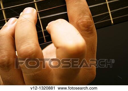 Stock Image - A close up view of musician's hand on guitar. Fotosearch