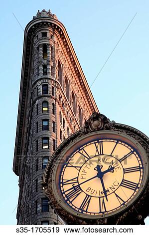Stock Photo - A closed up view of Flatiron Building before sunset with a sidewalk clock in foreground New York City New York USA.. Fotosearch