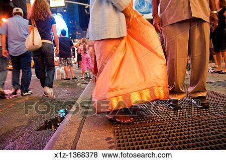 Stock Photo - A couple from Bangladesh is taking a photography on a subway grille in Times Square in Manhattan New York City. Fotosearch