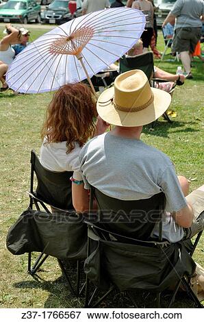 A couple listens to live music at an open air concert in the park, Ontario, Canada - Sunfest, festival of the sun, which celebrates the summer with music View Large Photo Image Stock Photo - A couple listens to live music at an open air concert in the park, Ontario, Canada - Sunfest, festival of the sun, which celebrates the summer with music. Fotosearch
