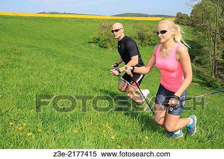 Stock Photography - a couple making nordic walking training through rural landscape.. Fotosearch